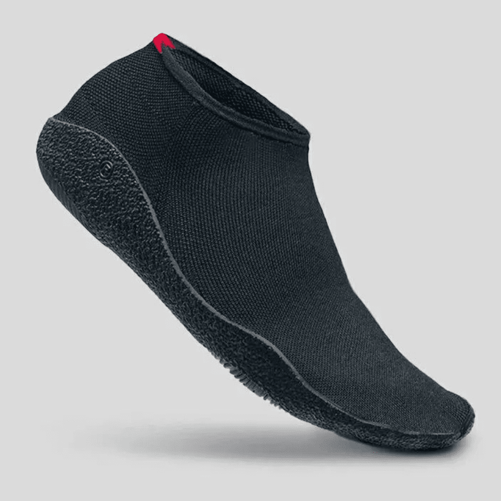 Sapatilha de treino preta minimalista de cano curto em tecido knit flexível, exibindo solado emborrachado texturizado e um pequeno detalhe vermelho no calcanhar.